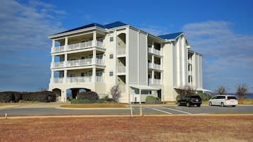 A multi-story hotel with a central entrance, balconies, and a parking lot.