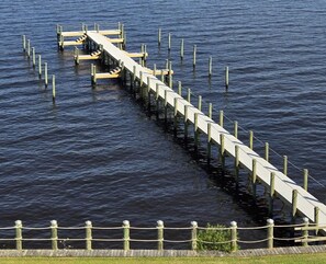 A wooden dock extending into a body of water, connected to a grassy area by a rope barrier. - Waterside Resort (Roper)
