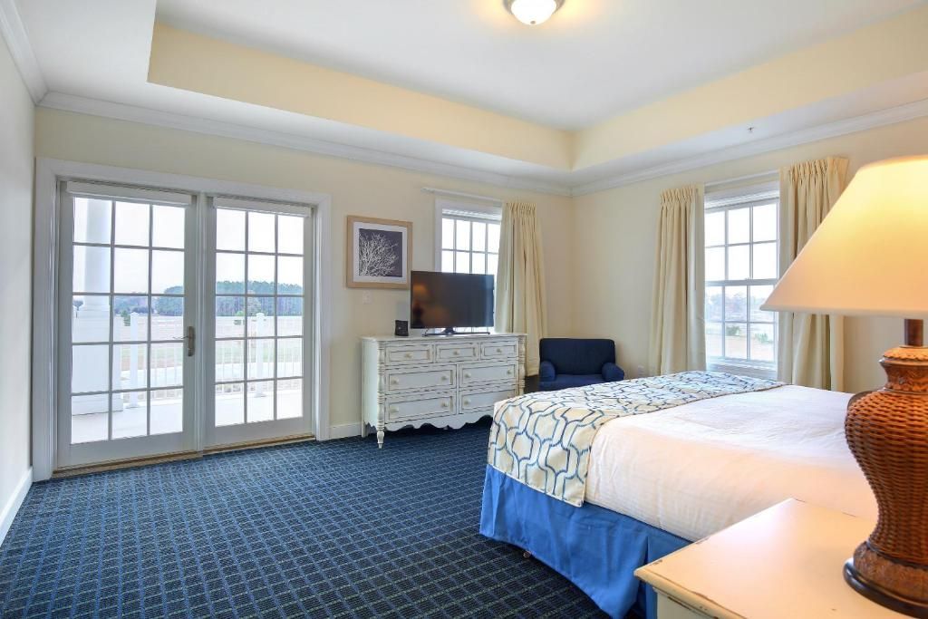 A hotel room with a bed, a dresser, a television, and a chair.