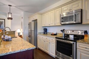A kitchen with a stainless steel refrigerator, a microwave, a stove, and granite countertops. - Waterside Resort (Roper)