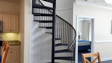 A modern interior with a spiral staircase, wooden dining table, and kitchen cabinets.