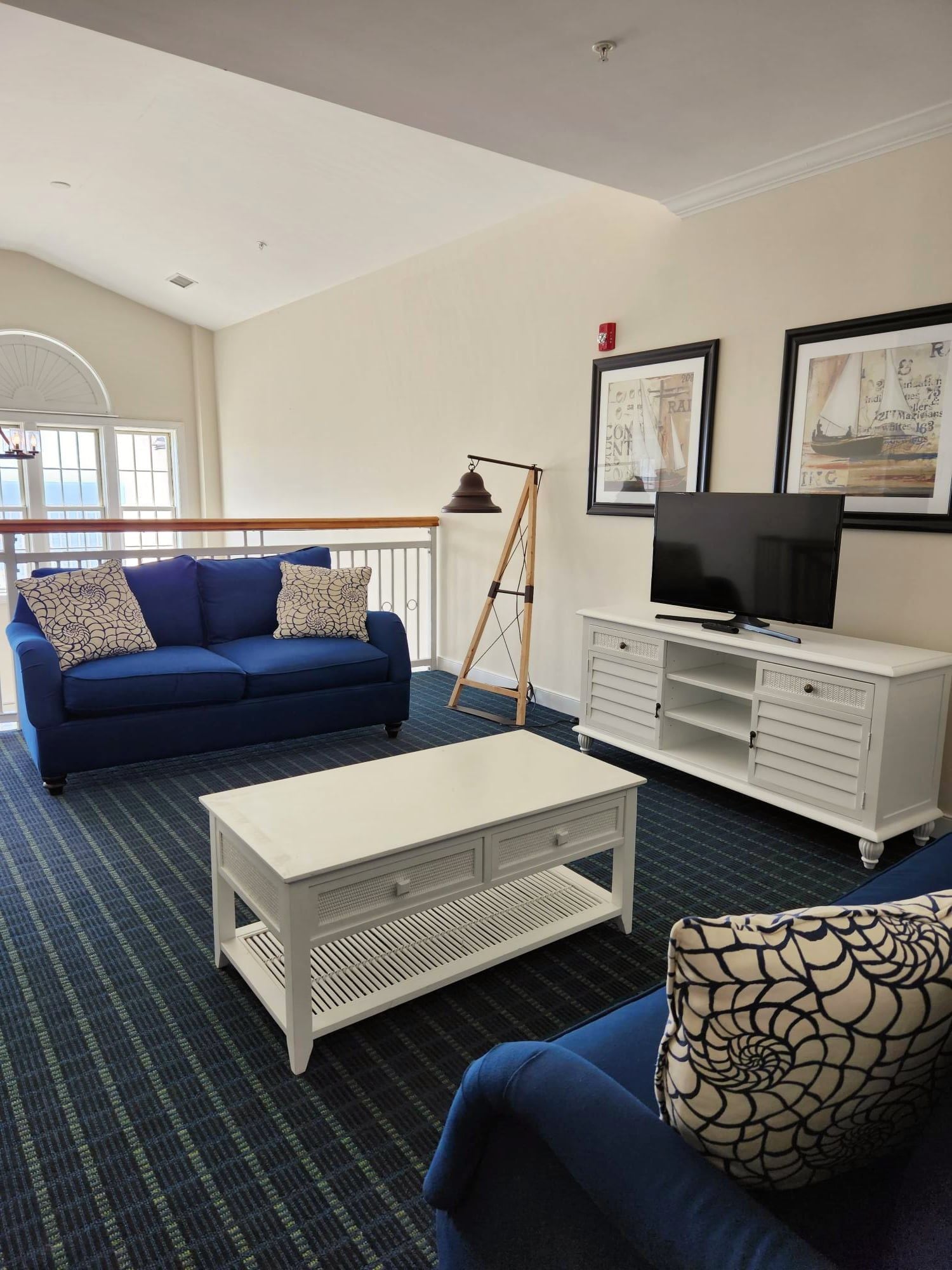 A modern living room with a blue sofa, white coffee table, and a TV on a white cabinet.