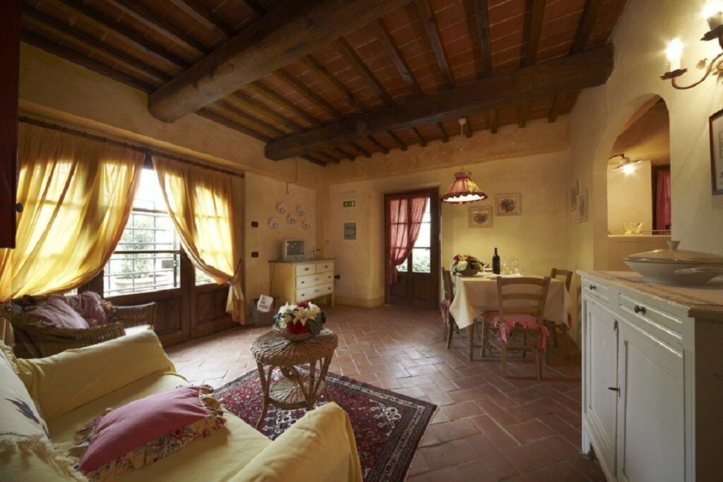 A cozy, rustic room with a wooden ceiling, a dining area with a table and chairs, and a kitchen area with a sink and cabinets.