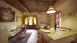 A cozy living room with a sofa, a coffee table, and a dining area with a table set for two. - Il Pollaio, one bedroom apartment walking distance to Tavarnelle Val di Pesa (Tavarnelle Val di Pesa)