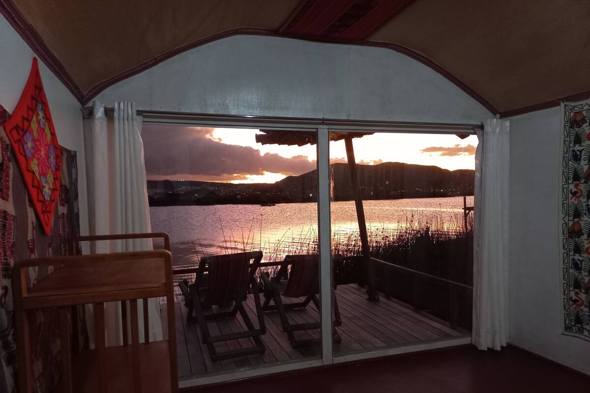 Une pièce dotée d’une grande porte-fenêtre coulissante qui donne sur une terrasse offrant une vue sur un plan d’eau au coucher du soleil.