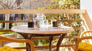 A round table with a white top, surrounded by wicker chairs with yellow cushions.
