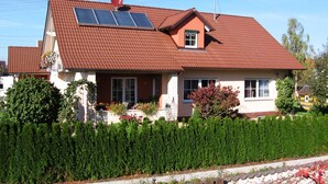 A house with a red-tiled roof, solar panels, and a well-maintained garden. - Family-friendly apartment near Legoland for 5 pers.                (Kammeltal)