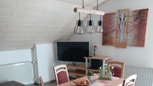A modern dining area with a wooden table, red upholstered chairs, and a large flat-screen TV. - Family-friendly apartment near Legoland for 5 pers.                (Kammeltal)