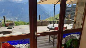 A wooden deck with potted plants and a view of mountains.