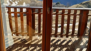 A wooden balcony with a view of snow-capped mountains.