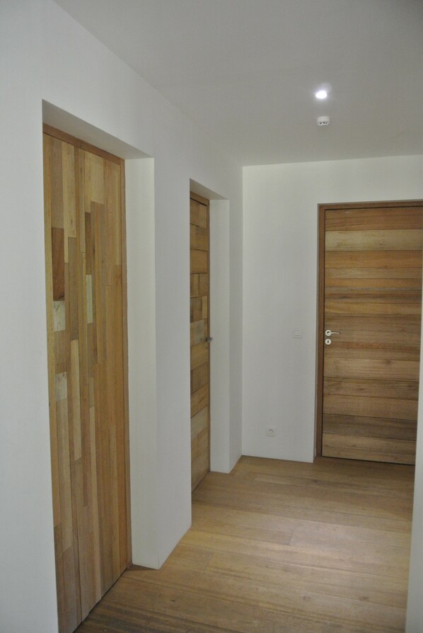Un couloir avec un plancher en bois et des portes.
