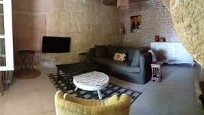 Una sala de estar con pared de piedra, un sofá, una mesa de centro y un televisor.