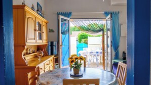 A dining area with a round table, chairs, and a colorful table runner. - La Marina - Charming Holiday Home in Residence with Swimming Pool (Saint-Cyprien)