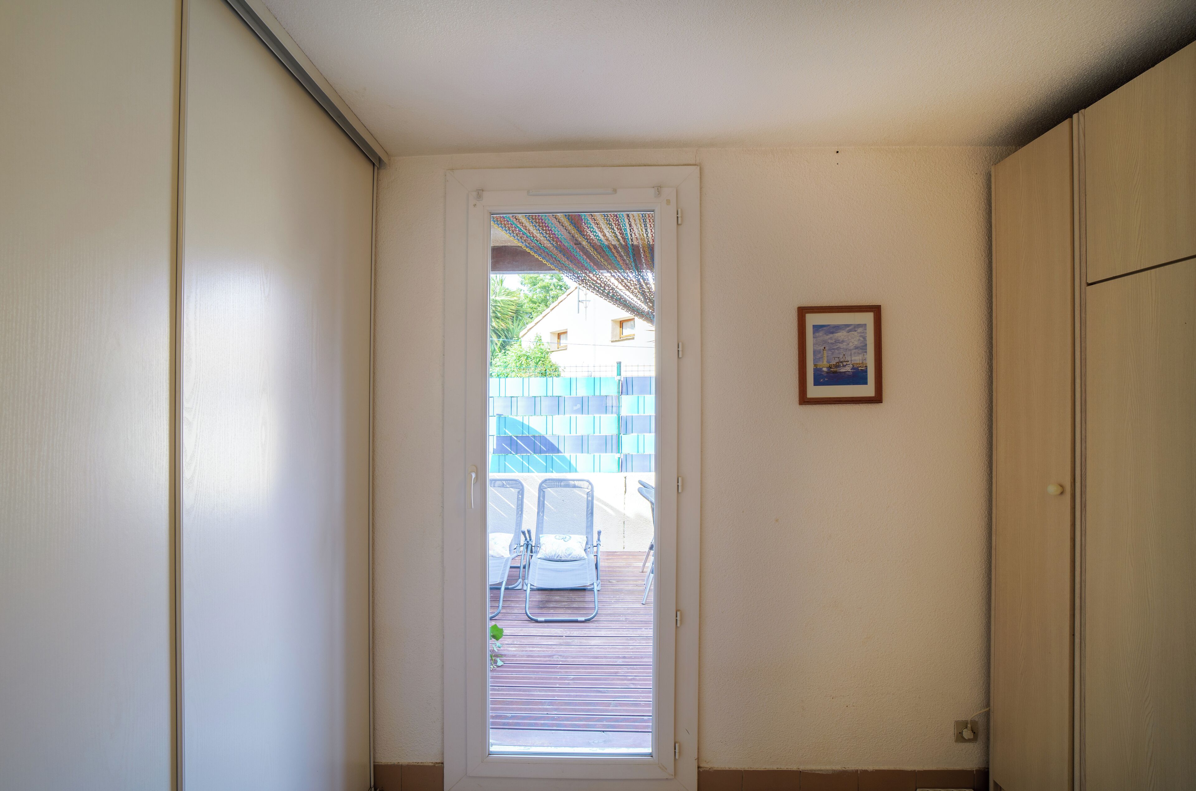 A doorway leading to an outdoor area with a wooden deck and two lounge chairs.