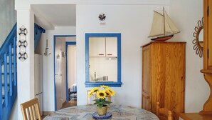 A dining area with a table set for two, a wooden cabinet, and a blue railing above. - La Marina - Charming Holiday Home in Residence with Swimming Pool (Saint-Cyprien)