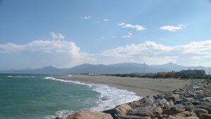 A coastal beach with rocky shoreline, distant mountains, and a clear sky. - La Marina - Charming Holiday Home in Residence with Swimming Pool (Saint-Cyprien)