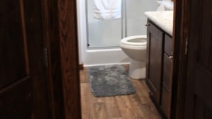 Ein schmales Badezimmer mit Dusche, Toilette und Holzschränken.
