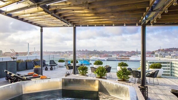 A rooftop terrace with a hot tub, seating area, and a view of the city and harbor. - Radisson blue riverside (Göteborg)