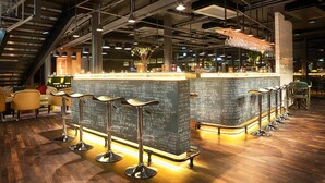 A bar area with a high ceiling, exposed ductwork, and a bar counter with stools. - Radisson blue riverside (Göteborg)