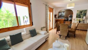 A modern living room with a sofa, dining table, and chairs. There is a kitchen area visible in the background. - Beautiful villa not overlooked, private pool, free WIFI, 2800m from beaches (Ametlla De Mar, L')