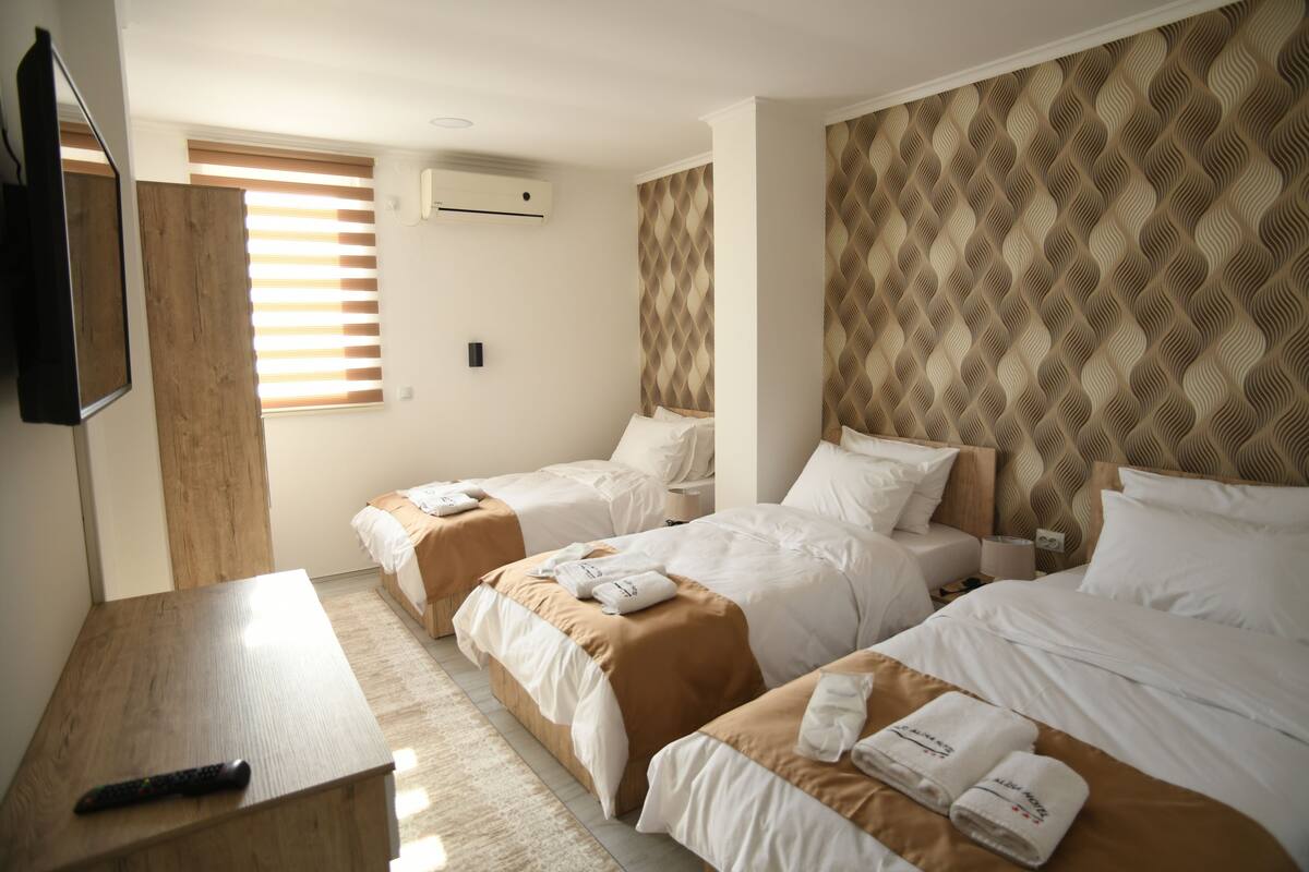 A hotel room with two beds, a TV, and a wooden desk.