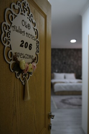 A wooden door with a welcome sign for Old Alisa Hotel, room number 206, and a bed visible in the background. - Hotel Old Alisa (Skopje)