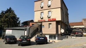 A hotel named "HOTEL ALBA" with a staircase leading to the entrance, parked cars, and a satellite dish. - Hotel Old Alisa (Skopje)