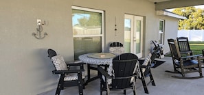 A patio with a round table and four chairs, a rocking chair, and a decorative anchor on the wall.