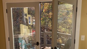 Eine Glastür mit Bär-Silhouette, die zu einer Holzterrasse mit Stühlen führt.