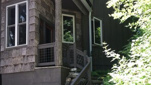 Eine Treppe führt zu einem Haus mit einer Steinfassade und einem Holengeländer.