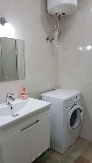 Bathroom features a sink, mirror, and front-loading washing machine.