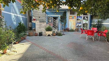 Un patio con escaleras, plantas en macetas y sillas rojas.