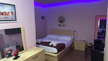 Un dormitorio con cama, mesitas de noche, cómoda, espejo y un cuadro en la pared.