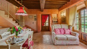 A cozy living room with a wooden ceiling, a dining area with a table set for two, and a comfortable armchair. - La Stalla, beautiful 2 bedrooms apartment in the Chianti region with pool & A/C (Tavarnelle Val di Pesa)