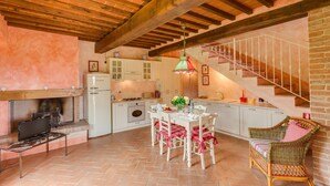 A spacious kitchen with white cabinets, a dining table, and a wicker chair. - La Stalla, beautiful 2 bedrooms apartment in the Chianti region with pool & A/C (Tavarnelle Val di Pesa)