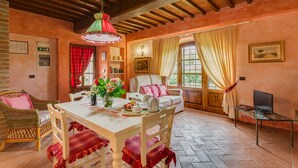A cozy room with a wooden ceiling, a dining table with chairs, a sofa, and a television on a stand. - La Stalla, beautiful 2 bedrooms apartment in the Chianti region with pool & A/C (Tavarnelle Val di Pesa)