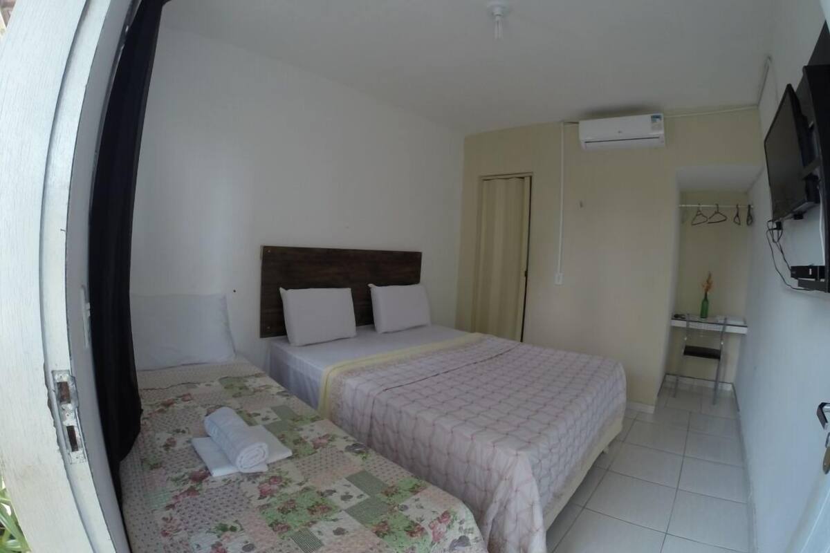 A bedroom with two beds, a TV, and a door leading to another room.