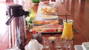 Montaje de un bufé de desayuno en un hotel, con una mesa larga, diferentes opciones de comida y una cafetera.