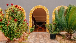 Un patio con tres puertas arqueadas, rodeado de plantas en macetas y un sendero de piedra.