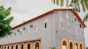 Un edificio con fachada gris, techo de tejas rojas y varios ventanales de arco.