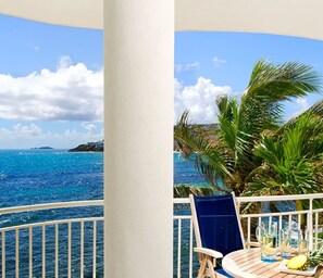 A balcony with a view of the ocean, a table with drinks and a pineapple, and a blue chair. - The Lighthouse at Oyster Bay Beach Club Resort (Upper Prince's Quarter)