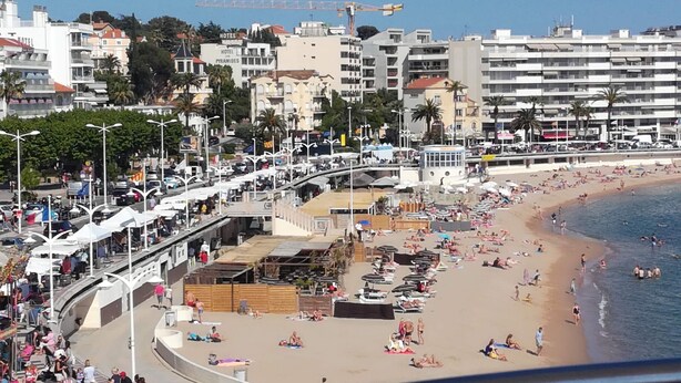 A beachside hotel with multiple floors, a promenade, and a beach with people sunbathing and swimming. - Superior 3-room villa (FREJUS)