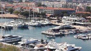 A marina with multiple yachts docked, surrounded by buildings and a mountainous backdrop. - Superior 3-room villa (FREJUS)