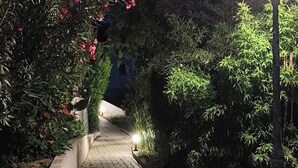 A wooden pathway flanked by lush greenery and a lit lamp post. - Superior 3-room villa (FREJUS)