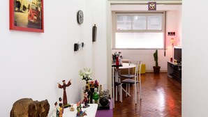 A hallway with a white table displaying various decorative items, a purple bench, and a wooden floor. - Omar do Rio - NSC1001 (Rio de Janeiro)