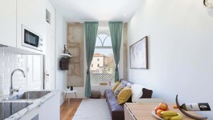 A compact kitchen with a sink, microwave, and a view through a window with curtains.
