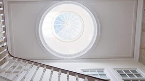 A grand staircase with a circular skylight leading to a balcony.