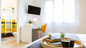 A neatly arranged bedroom with a bed, bedside table, and a TV mounted on the wall. - Il Nocciolo 12, Emma Villas (Cecina)