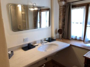 A bathroom with a large mirror, a sink, and a small round mirror on the countertop.