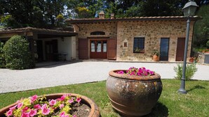 A stone building with a gravel driveway, a large flower pot, and a lamp post. - Glicine, romantic cottage with outdoor patio, on the hills of San Gimignano (San Gimignano)